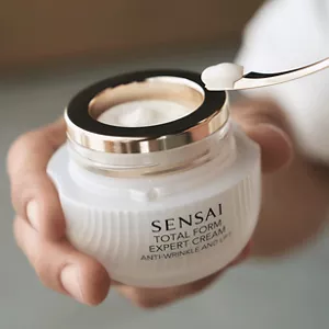 Close up of person scooping out product of Total Form Expert Cream jar with spatula